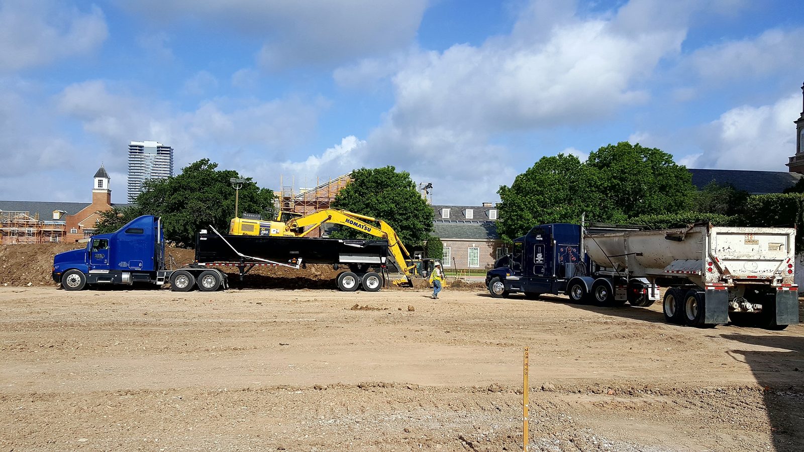 GMS end dump trailer and dump trucks staged at downtown Houston construction site with city skyline
