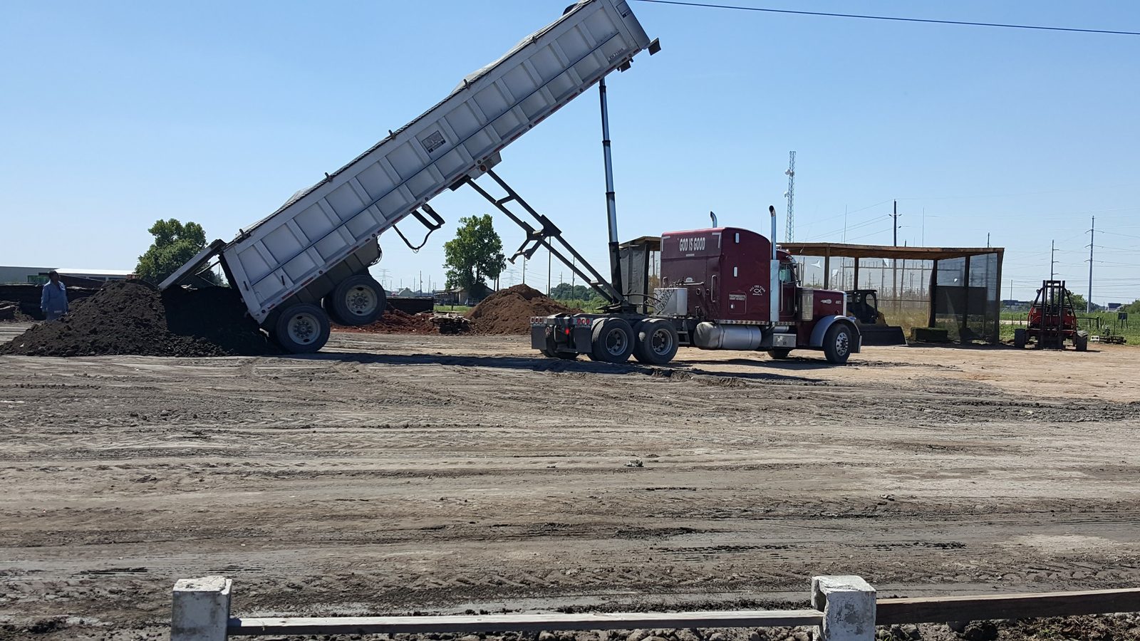 GMS dump truck unloading topsoil material at Houston-area jobsite with raised dump bed